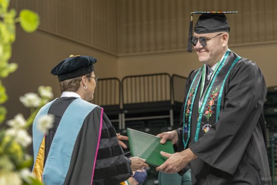 A Bemidji State University graduate receiving a diploma