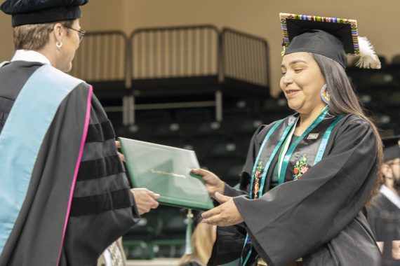 A Bemidji State University graduate receiving a diploma