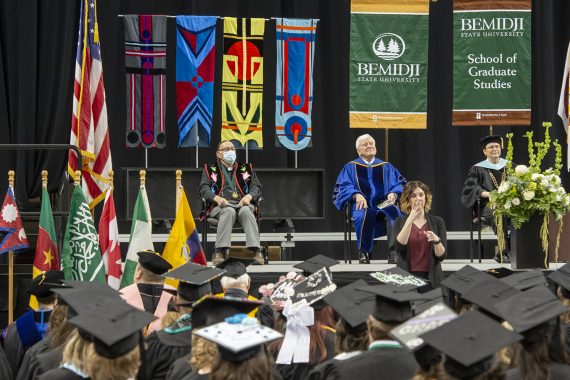 Graduates sitting and listening to a commencement address