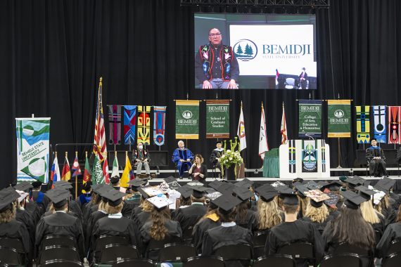 Graduates sitting and listening to a commencement address