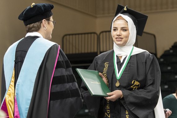 A Bemidji State University graduate receiving a diploma