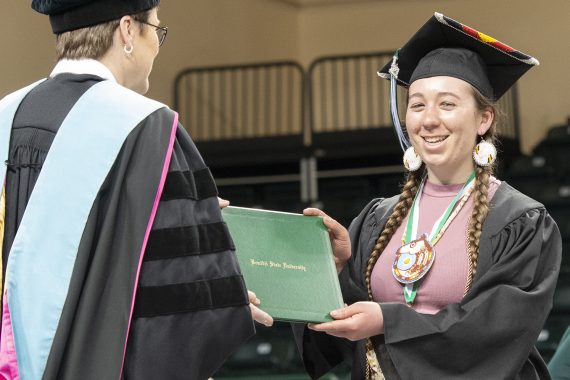 A Bemidji State University graduate receiving a diploma