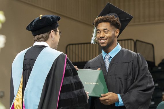 A Bemidji State University graduate receiving a diploma