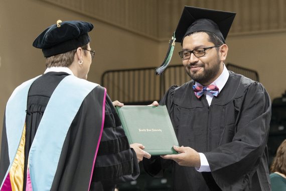 A Bemidji State University graduate receiving a diploma