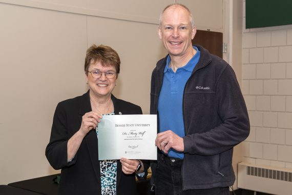 President Faith Hensrud presenting Dr. Marty Wolf, professor of mathematics and computer science, a retirement certificate.