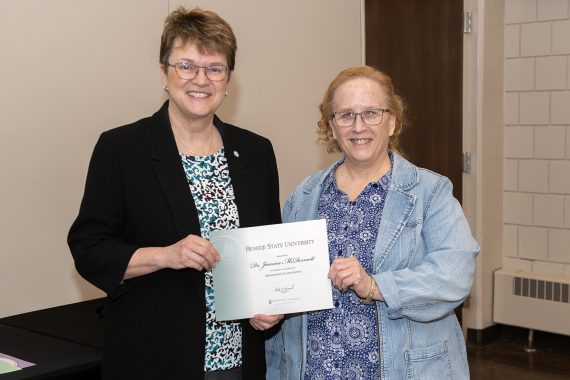 President Faith Hensrud presenting Dr. Jeanine McDermott, associate professor of nursing, a retirement certificate.