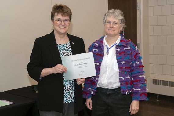 President Faith Hensrud presenting Dr. Co Livingston, professor of mathematics and computer science, a retirement certificate.