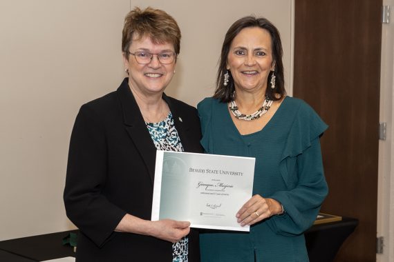 President Faith Hensrud presenting Margie Giauque, director of career services, a retirement certificate.