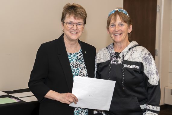 President Faith Hensrud presenting Cheryl Davis, general maintenance worker, a retirement certificate.