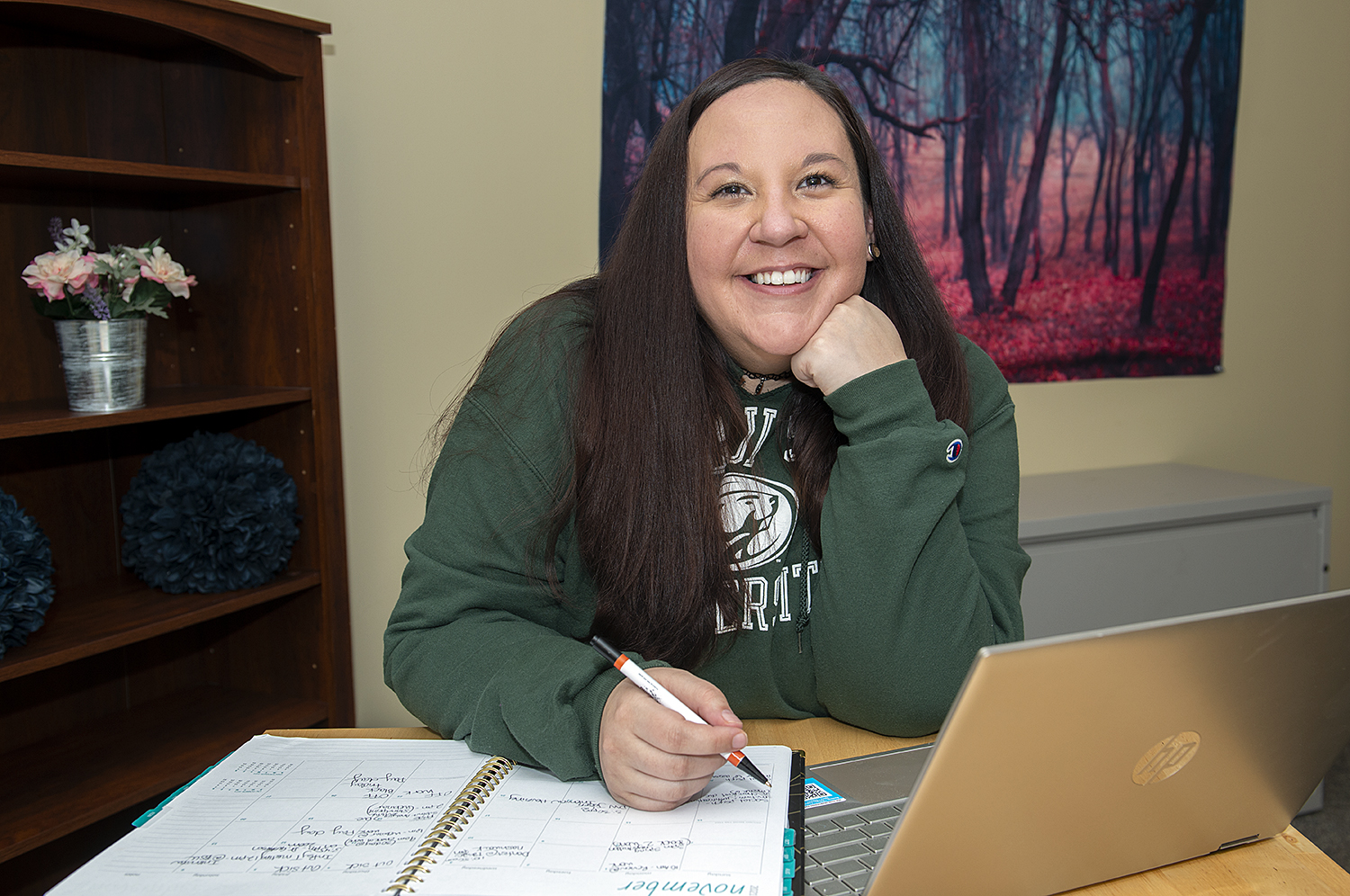 Ashley Spry sitting at her office desk with her computer and notebooks