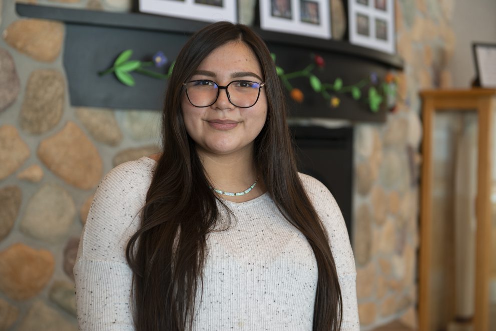 Michelle Anderson standing in front of a fireplace in the American Indian Resource Center at Bemidji State