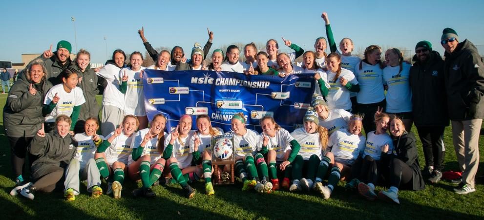 Bemidji State Women's Soccer team standing in front of the NSIC Championship banner