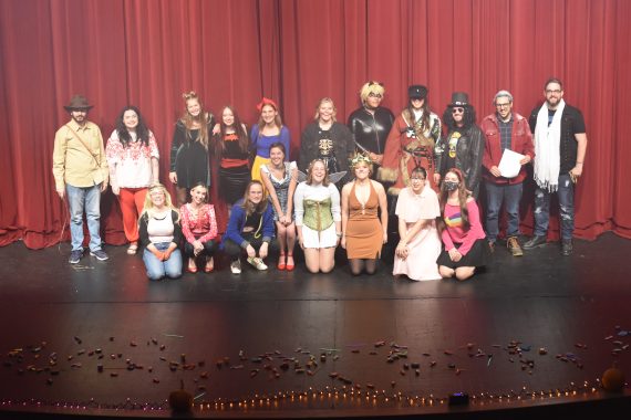 Students in costume posing in a group on the stage