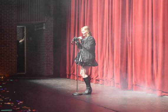 Student reading at the microphone in a costume