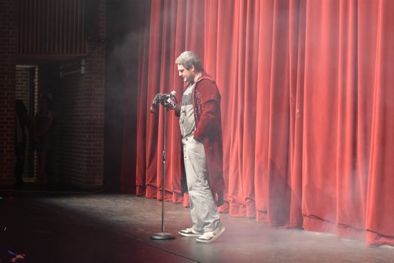 Student reading at microphone on stage