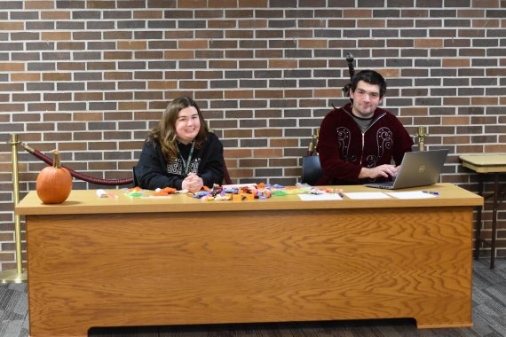 Two students sitting behind a desk, smiling