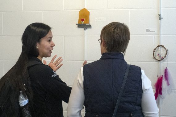 A student speaks to an attendee at the traditional Ojibwe crafts gallery Dec. 5