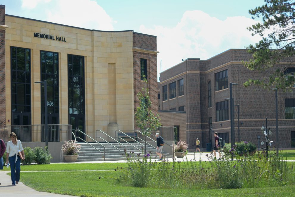 Students walk on campus in front of Memorial Hall