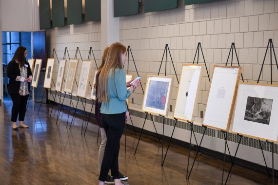 Event attendees look at an art display at the Women's History Month Keynote and Dinner event