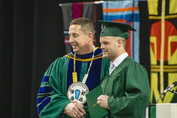 BSU President John Hoffman takes a photo with a student during the commencement ceremony