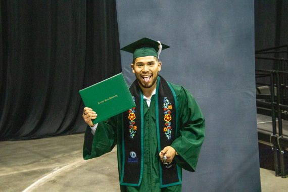 A graduate poses with their diploma