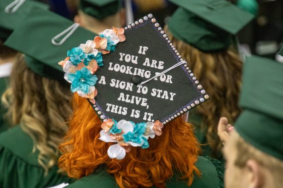 A graduation cap decorated with the phrase "If you are looking for a sign to stay alive, this is it."