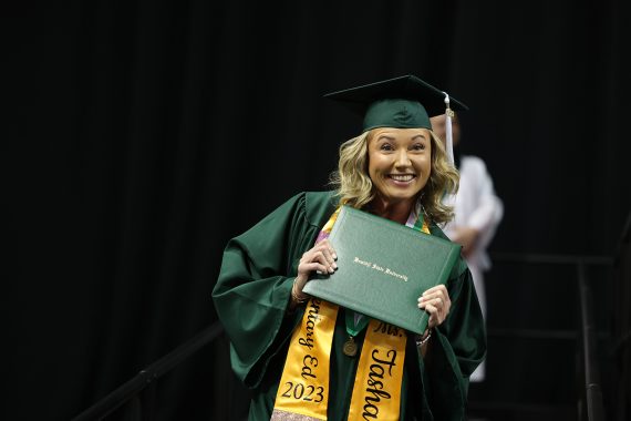 A BSU student smiles while holding their diplima