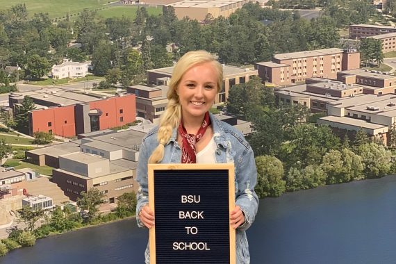 Bre poses with a "first day of school" sign