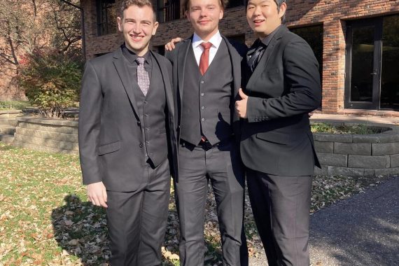 Three BSU students pose in front of a brick building.