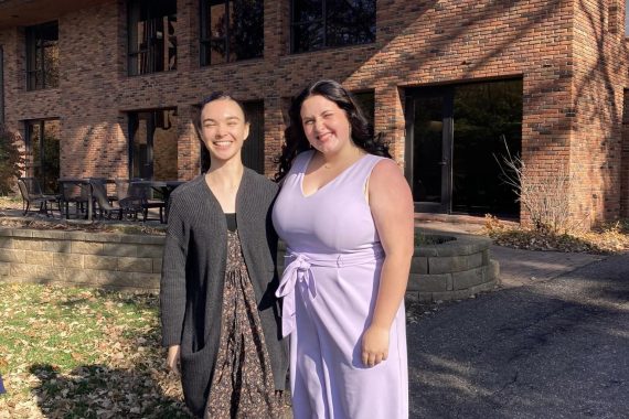 Two BSU students pose in front of a brick building.