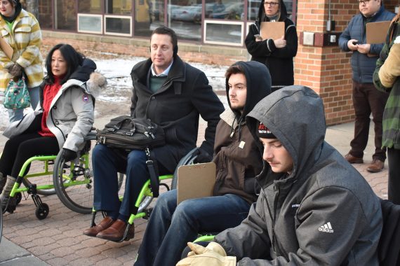 BSU President John L. Hoffman in a wheelchair, joined by several students and his wife, Joy.