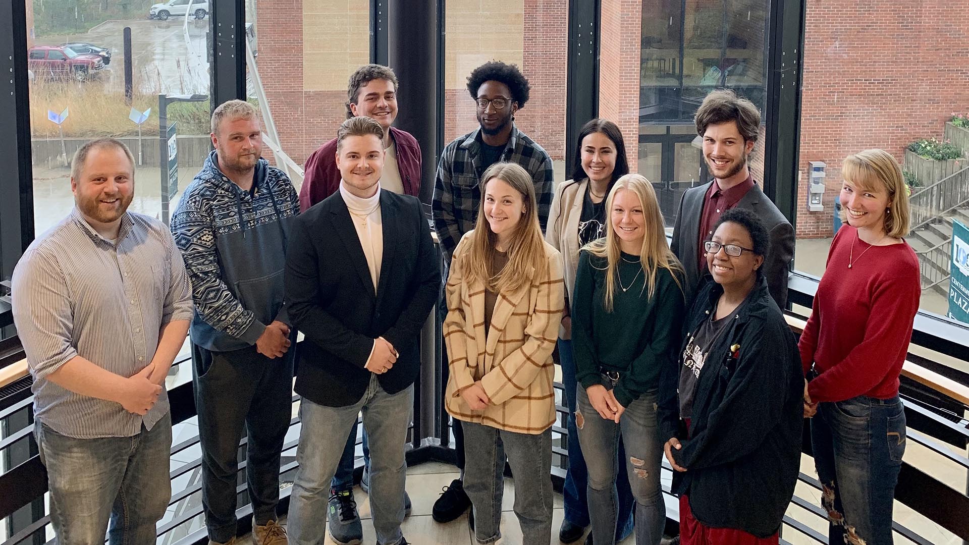 Students and their faculty advisor pose in front of the window in the Memorial Hall stairway, overlooking the BSU campus.