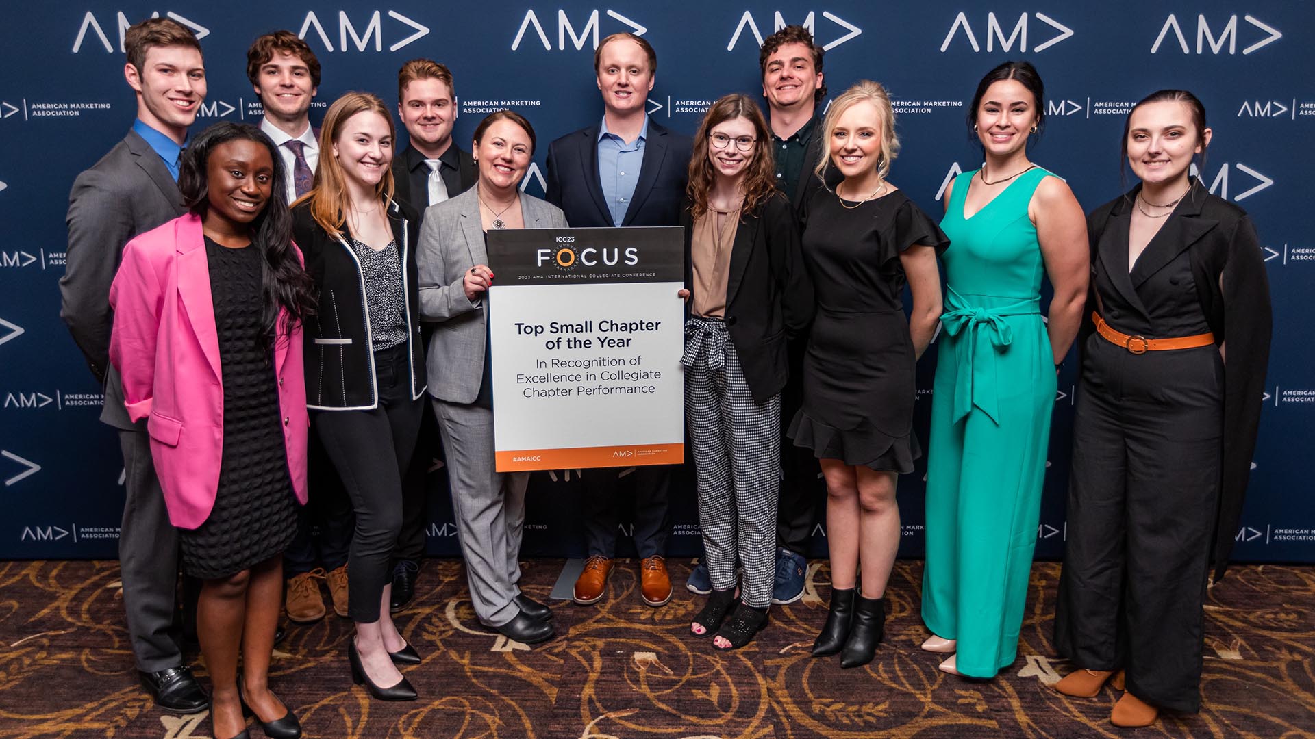 A group of students posing with a sign in front of a blue background with the American Marketing Association logo