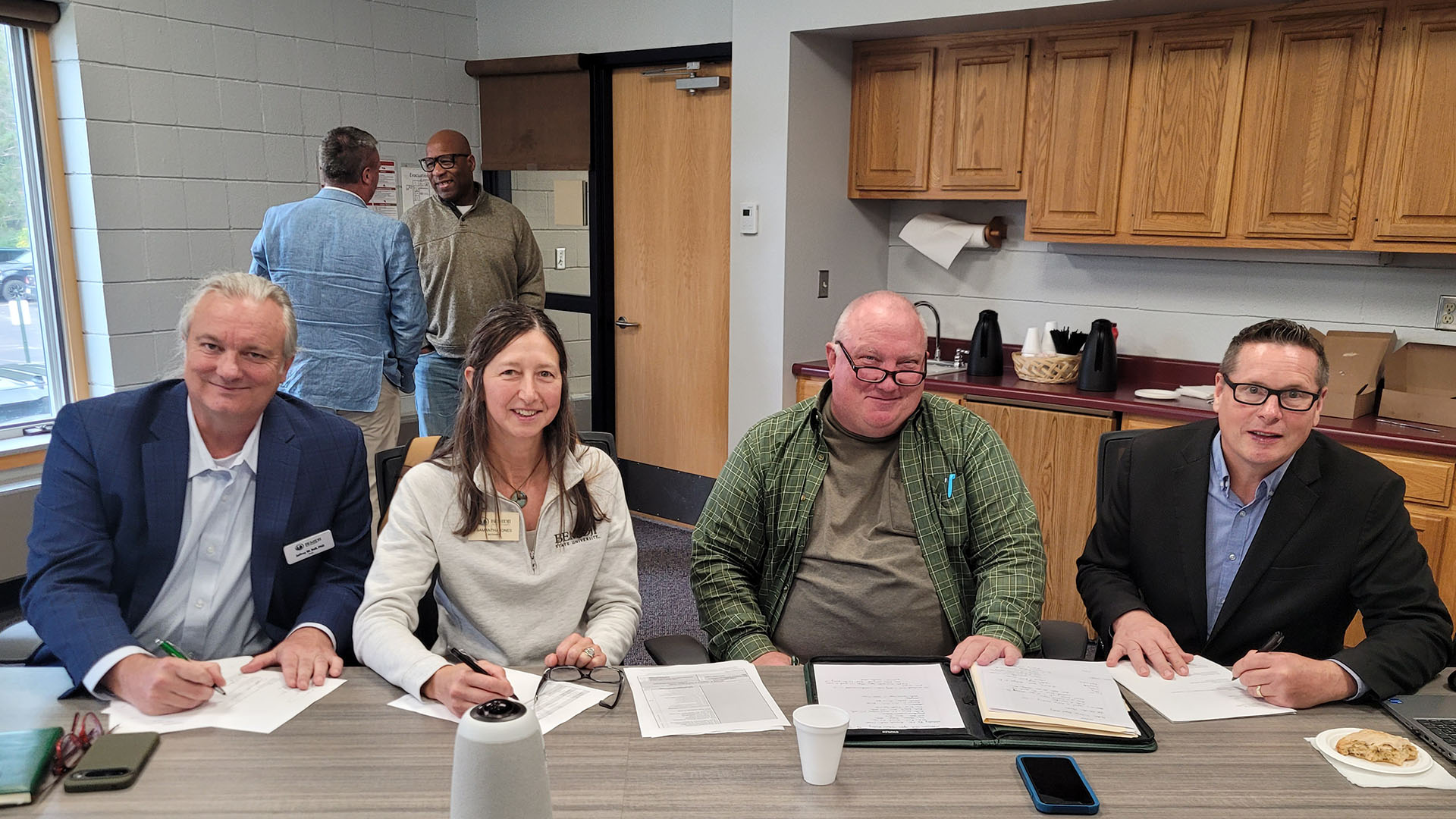 Two administrators from BSU and two from Minnesota North collge sit at a table and are signing contracts.
