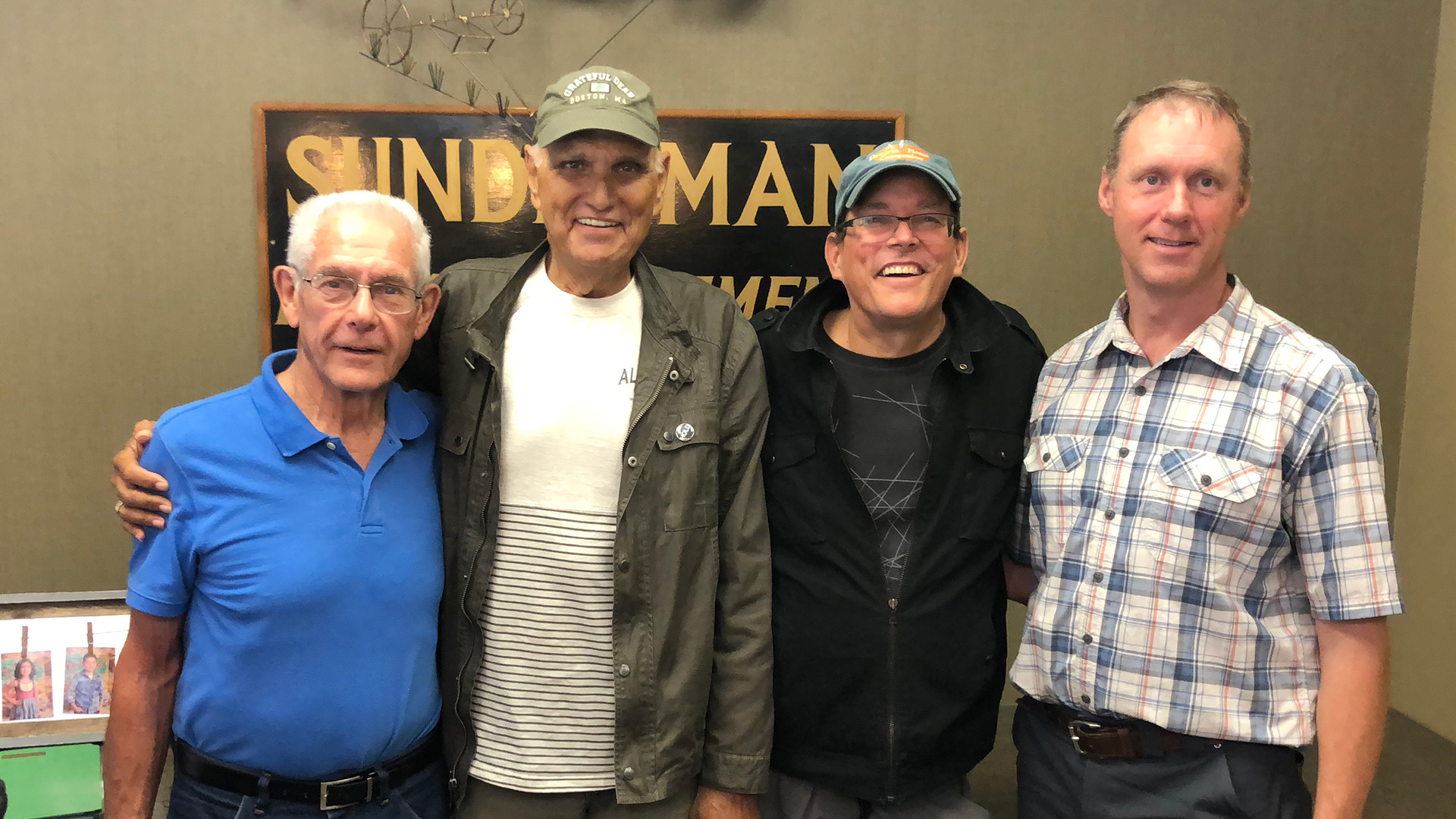 Pictured from left to right: Brian Larson, Allen Sunderman, Dan Koskovick and Brent Larson. They are standing in front of a wall with a sign that reads "Sunderman Farm Management Co."