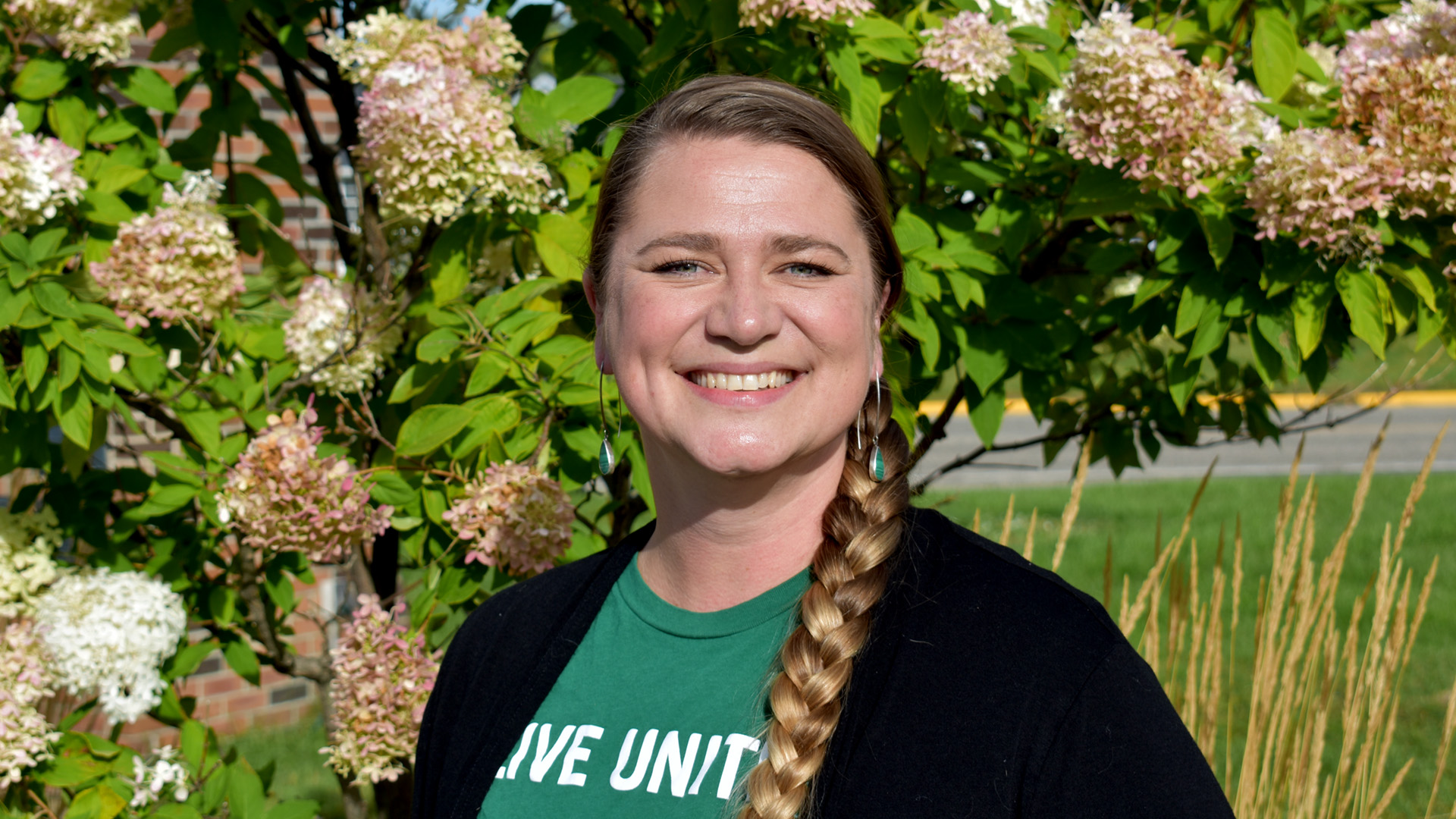 A portrait of Dr. Anna Carlson; flowering trees with white blossoms are in the background