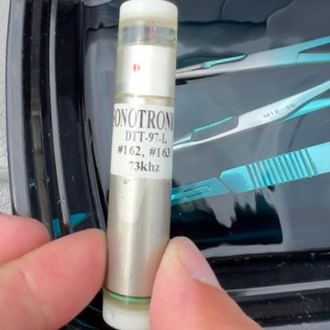 A muskie tracking capsule that looks like a chap-stick tube — a small, silver cylinder with a transparent top.