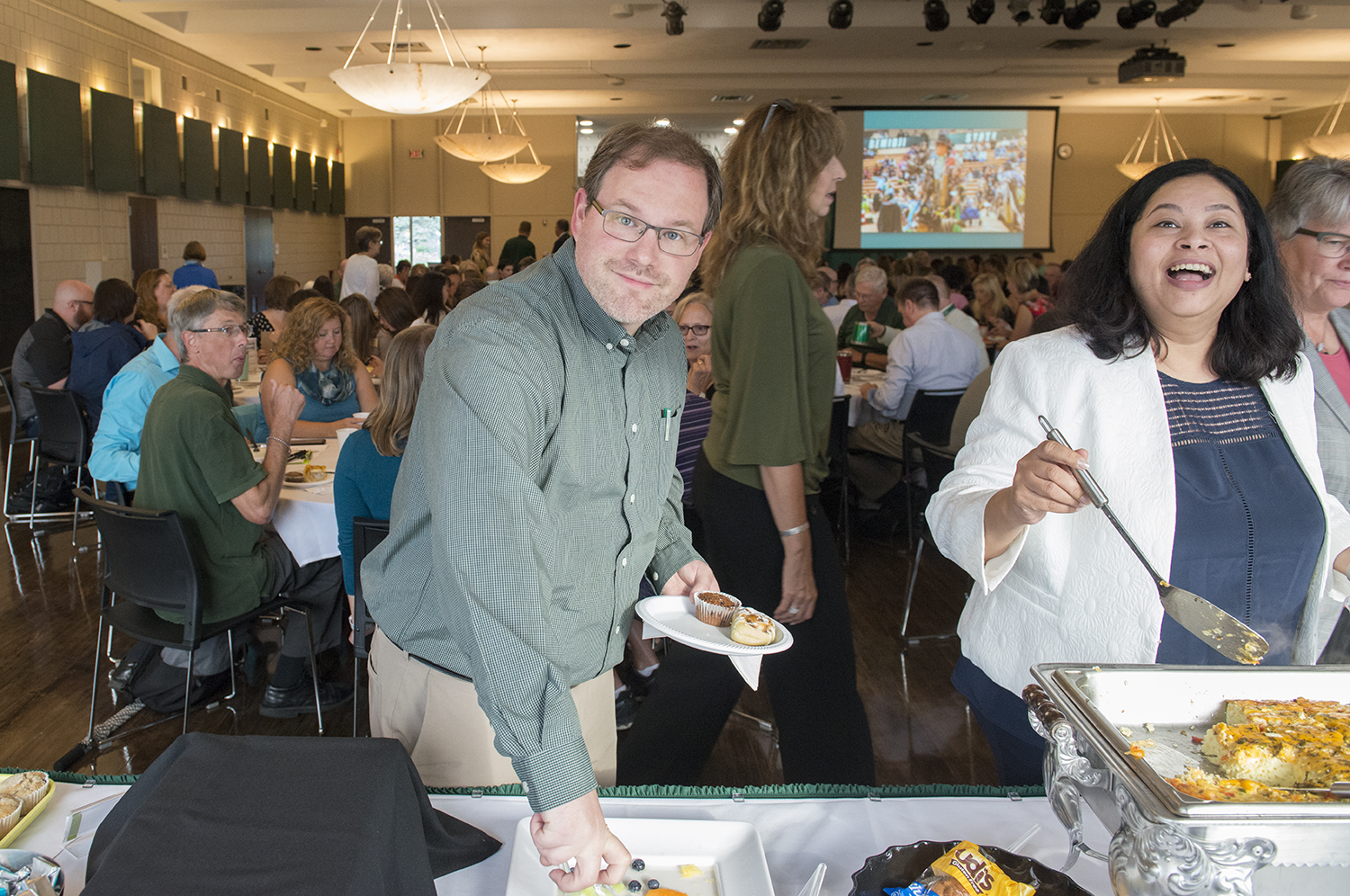 Two faculty members in line getting breakfast