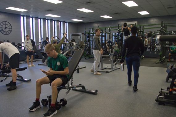 A group of students using equipment in a weight room