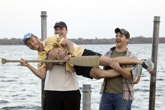 Two BSU students carrying another student on a dock