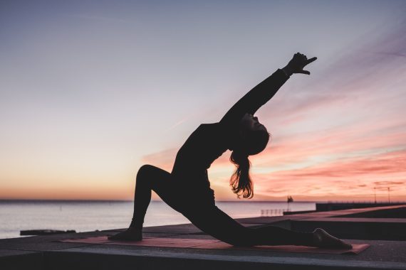 Woman in a yoga pose on a lake dock