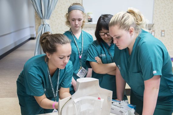 Bemidji State nursing students gathered around a medical instruments station