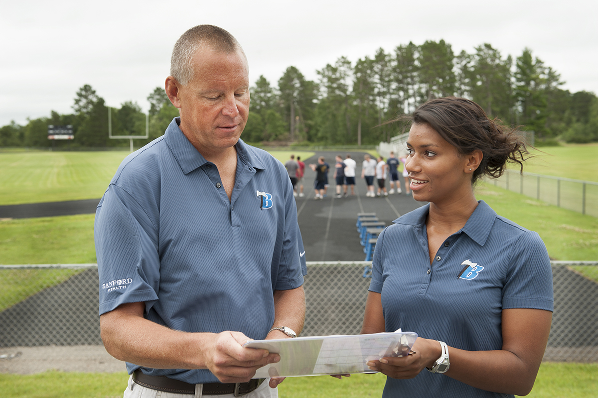 Mentor providing instruction to an intern outside of an outdoor track