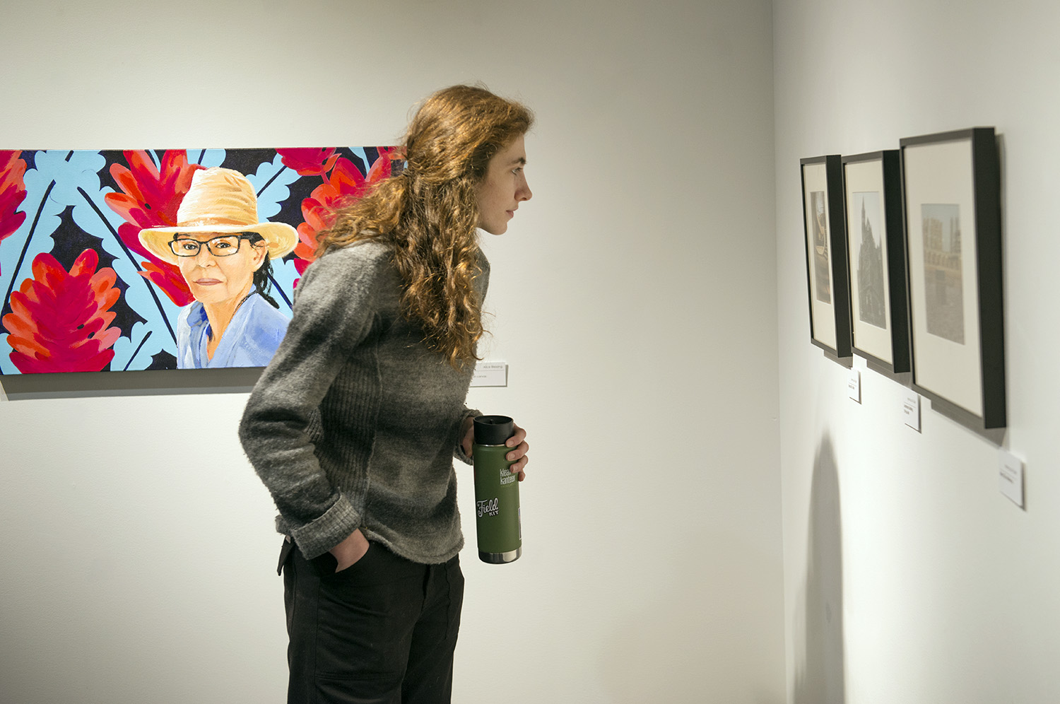 Bemidji State student admiring drawings during a TAD Faculty Art Show 2019