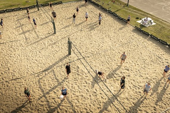 Students playing on the sand volleyball courts in front of Oak Hall