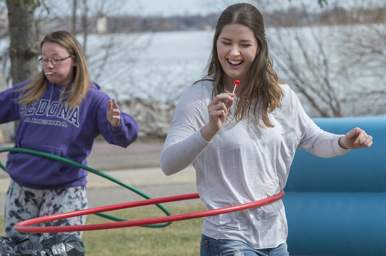 BSU student eating an ice cream while hula hooping in front of Lake Bemidji