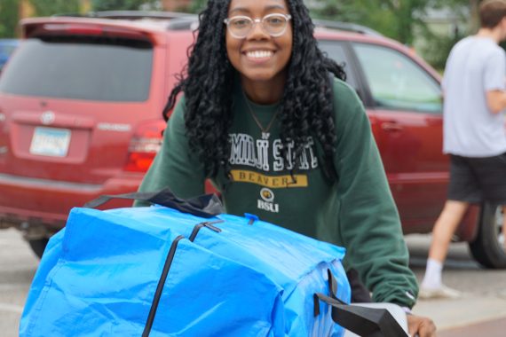 College student pushing a bin full of packages on move in day 2022