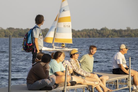 Students sitting on a dock in lake bemidji