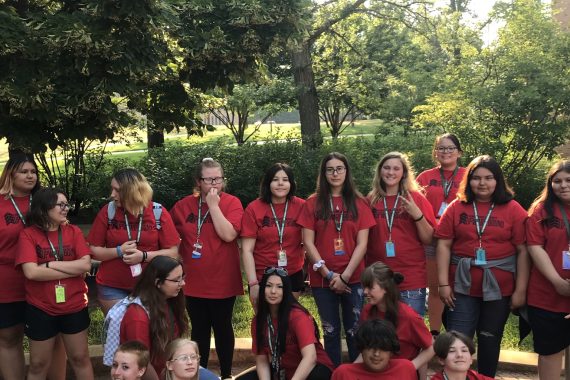 Group of students in red t-shirts and badges standing outside